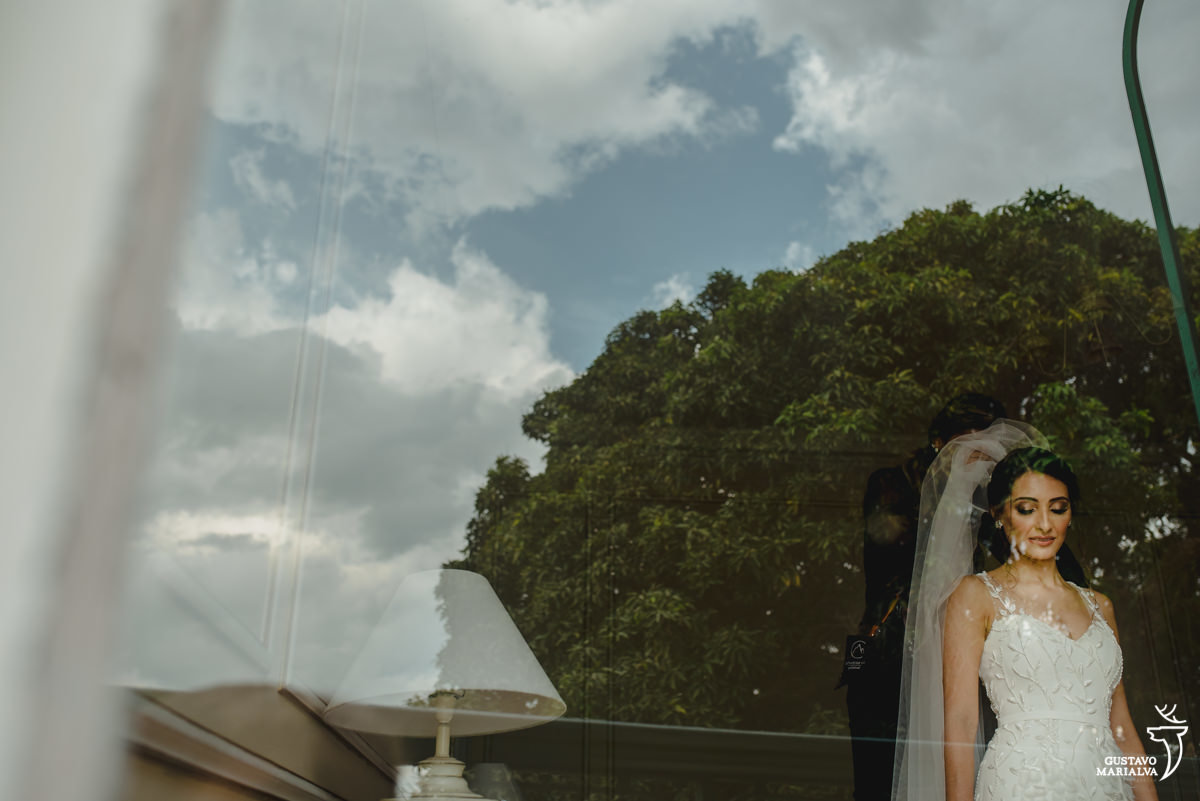 noiva olha para baixo enquanto maquiadora monique caetano coloca véu em sua cabeça 