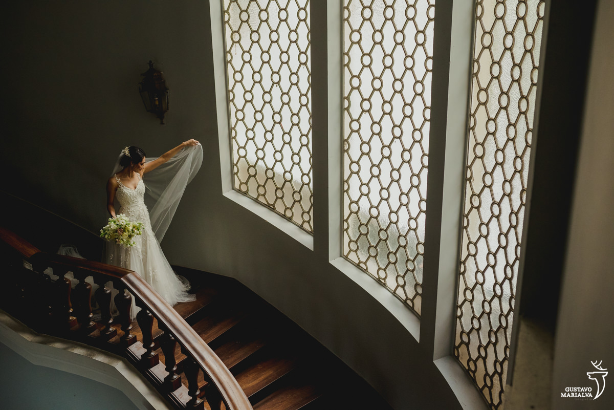 noiva arruma o véu enquanto segura o buquê nas escadas da mansão santa teresa