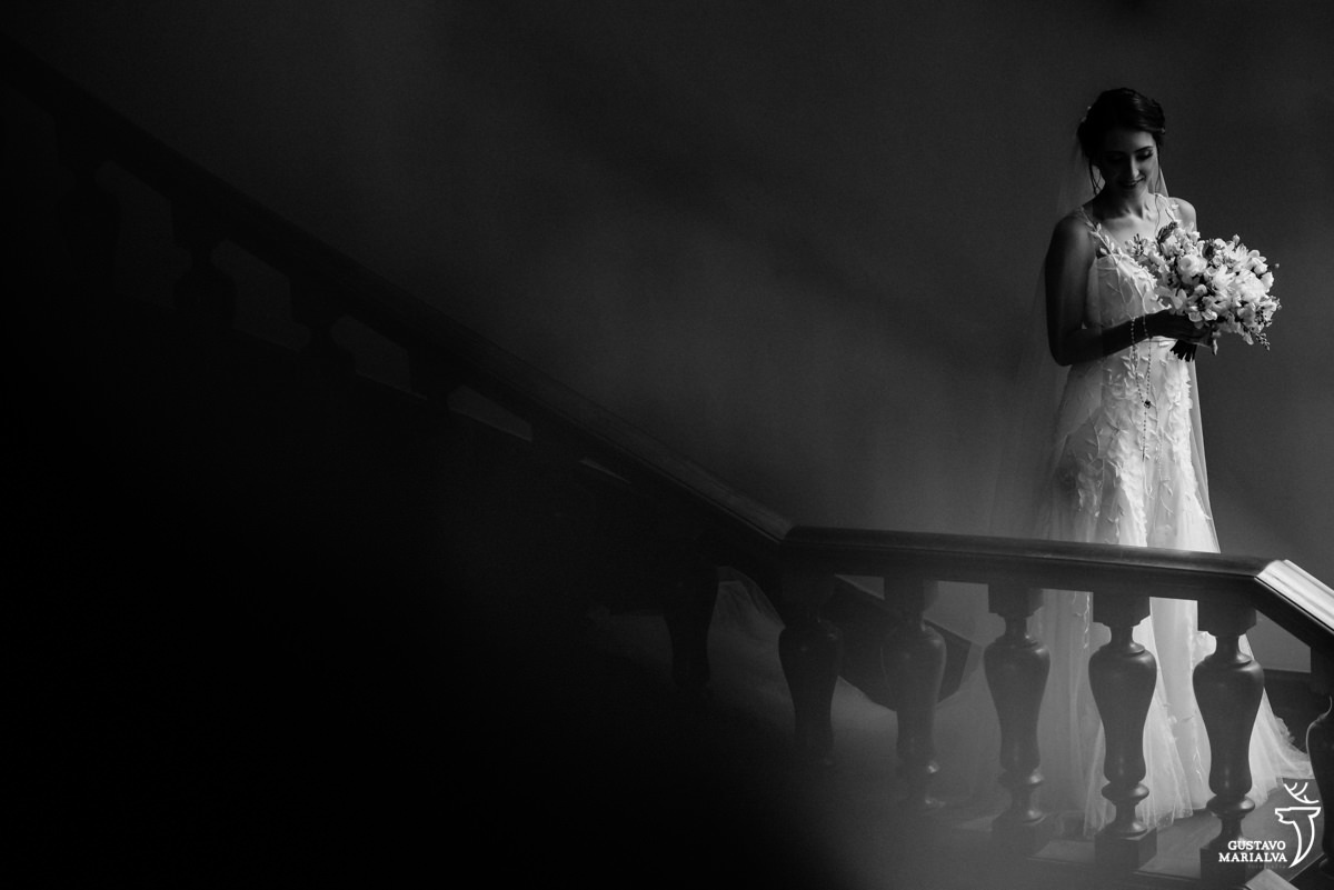 noiva arruma o buquê nas escadas da mansão santa teresa durante sessão de retratos no making of do casamento