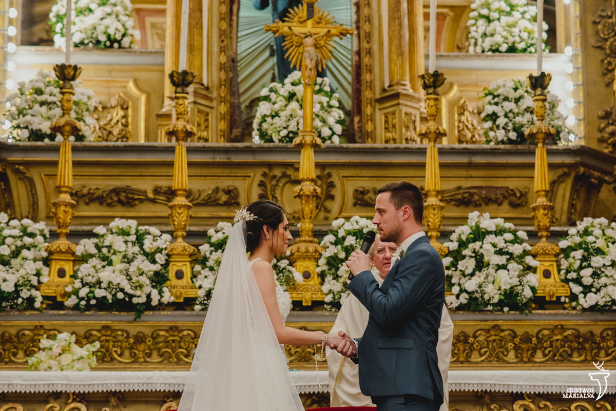 noivo usando terno azul fala os votos para a noiva durante a cerimônia de casamento