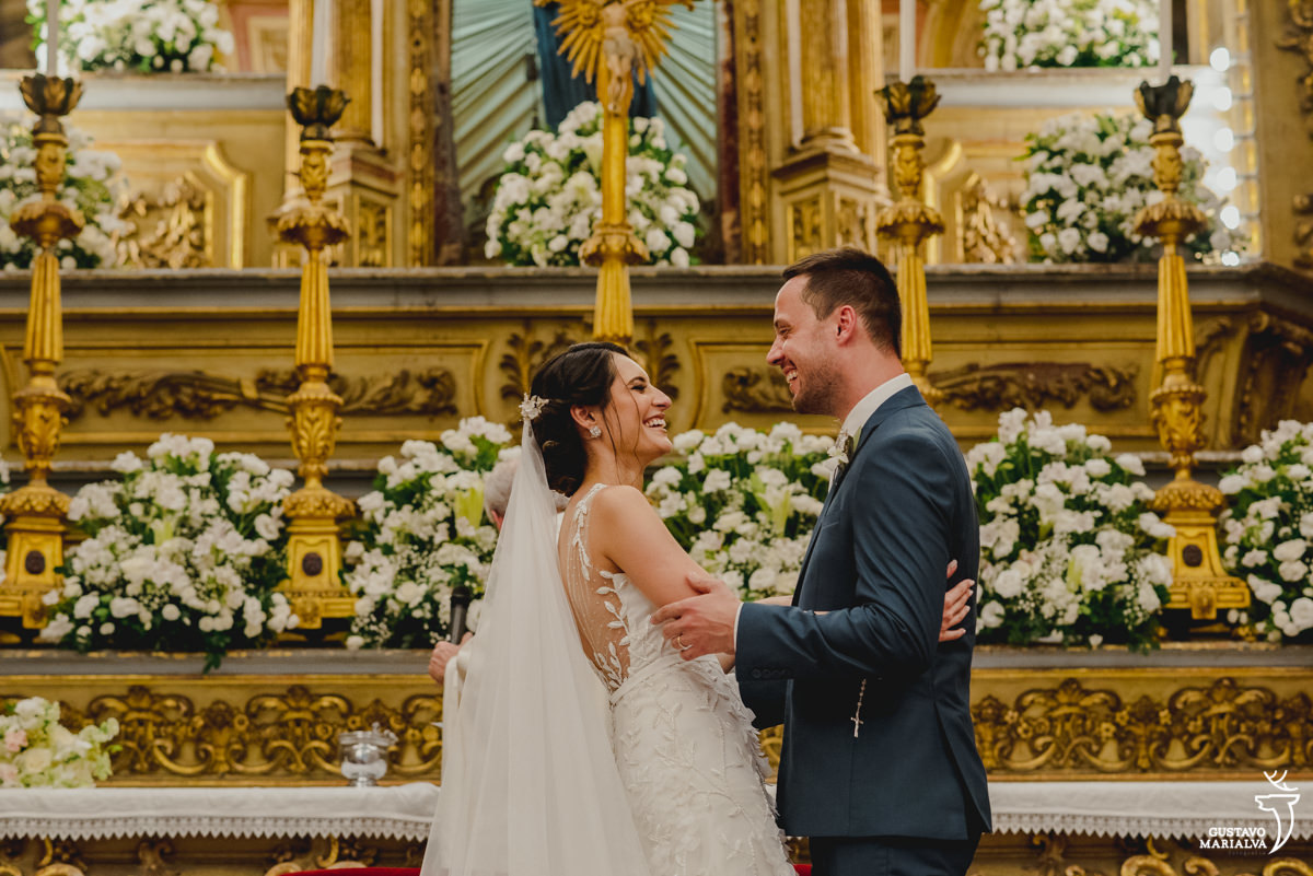 noivos sorriem abraçados durante a cerimônia de casamento