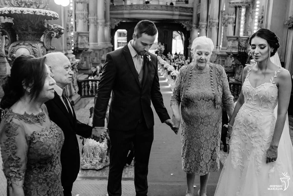 noivo dá as mãos para os avós e noiva de olhos fechados reza