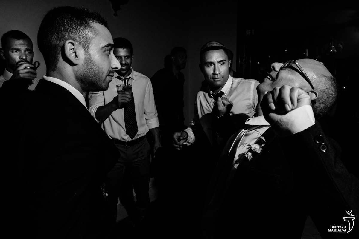 homem careca e de óculos dança enquanto é observado pro amigo que faz careta