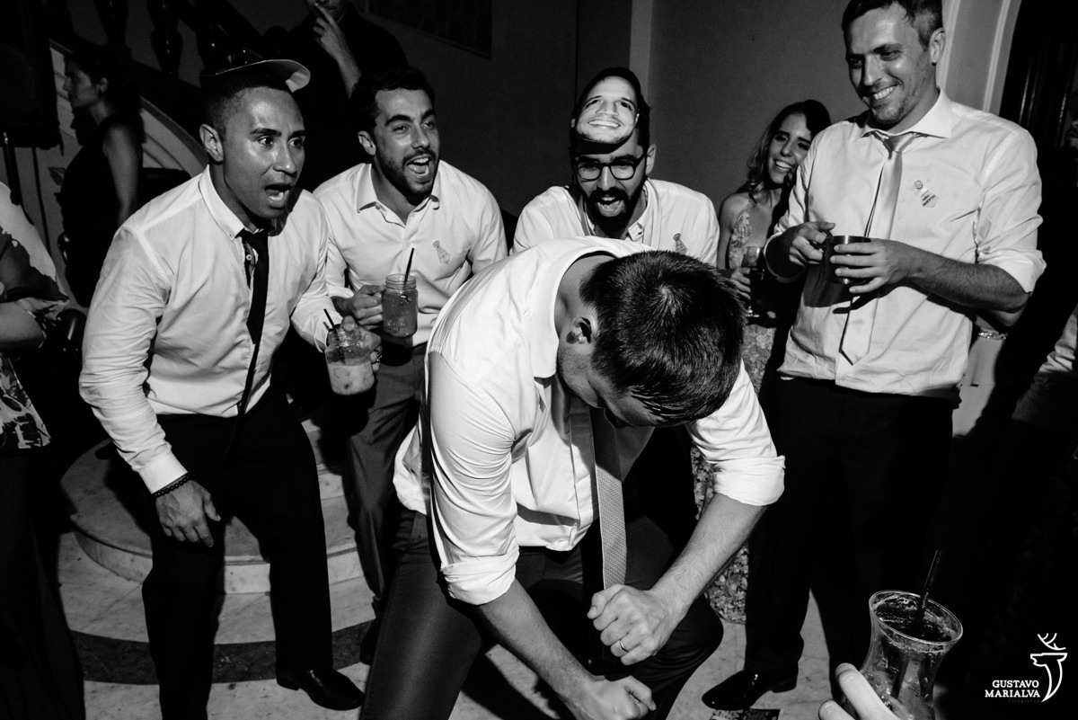 noivo dança enquanto amigos usando máscara acompanham sorrindo