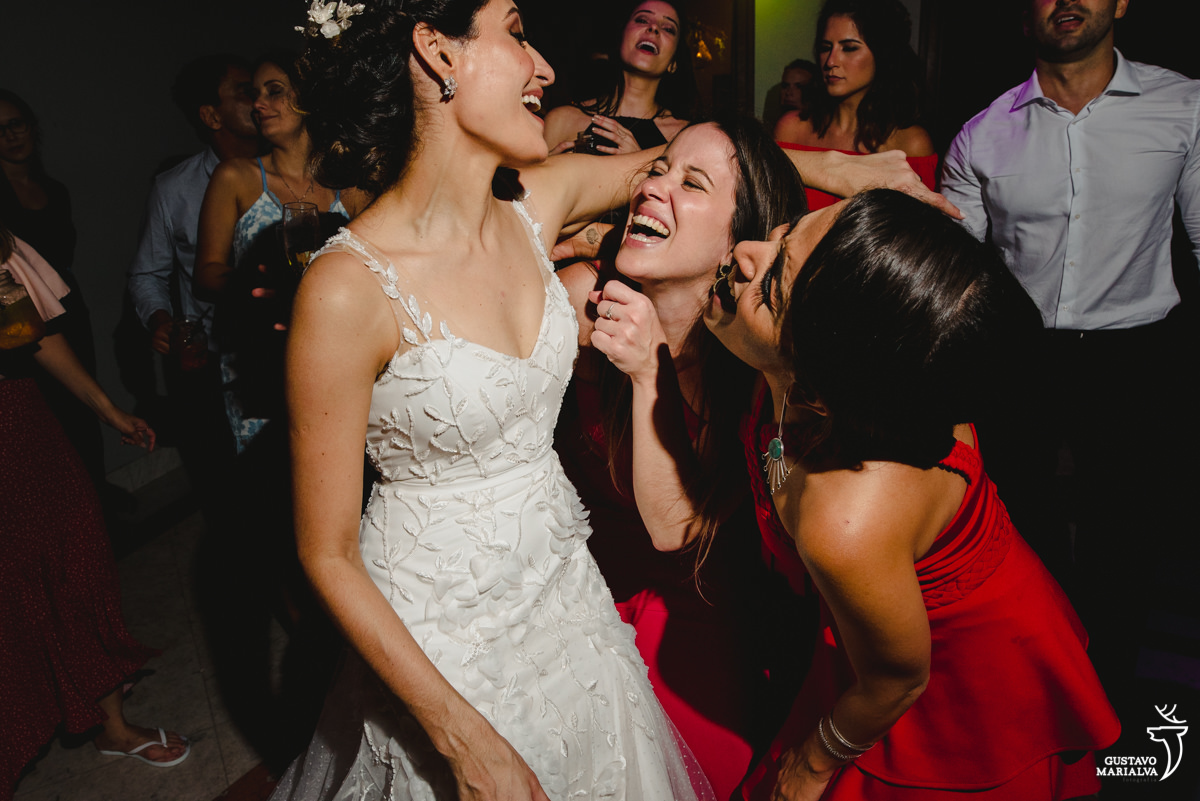 noiva dança e sorri com amigas que usam vestido vermelho