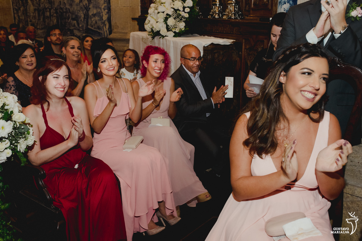 madrinhas usando vestido rosa e vermelho sorriem e aplaudem