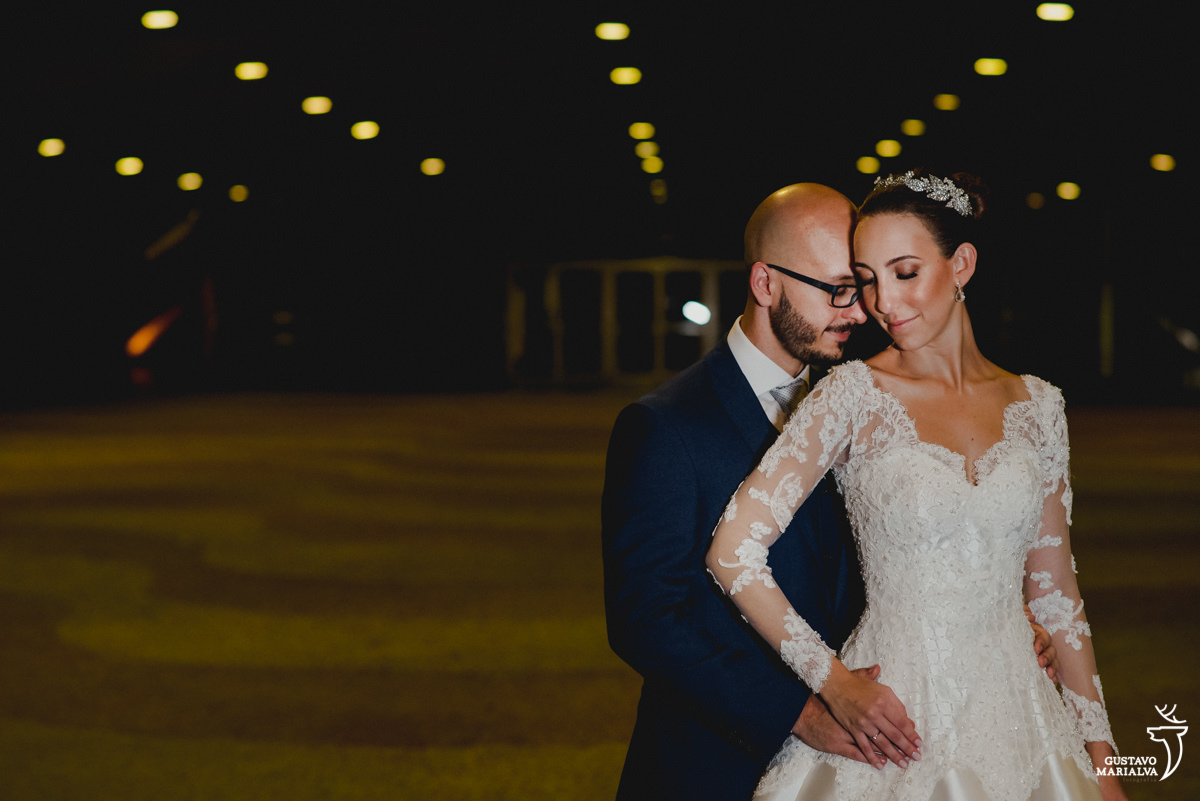 noivo usando terno azul marinho abraça a noiva por trás no pátio do Mam