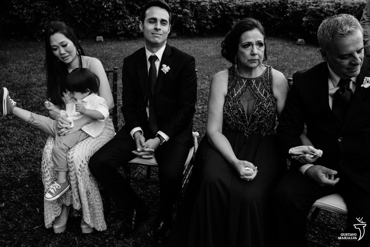 casal chora ao ouvir a cerimônia de casamento enquanto menino brinca no colo da mãe