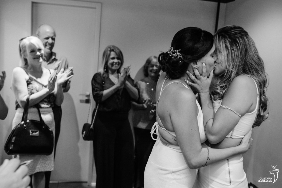 noivas se beijam e são aplaudidas por familiares durante o casamento civil