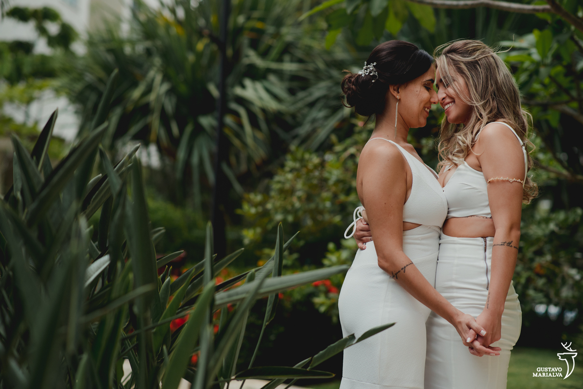noivas se abraçam e colam testa com testa usando vestido branco