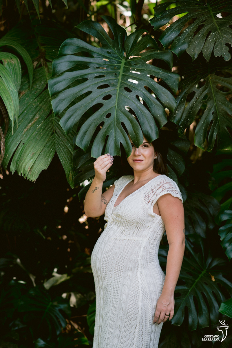mulher grávida usando vestido branco cobre o rosto com a planta costela de adão