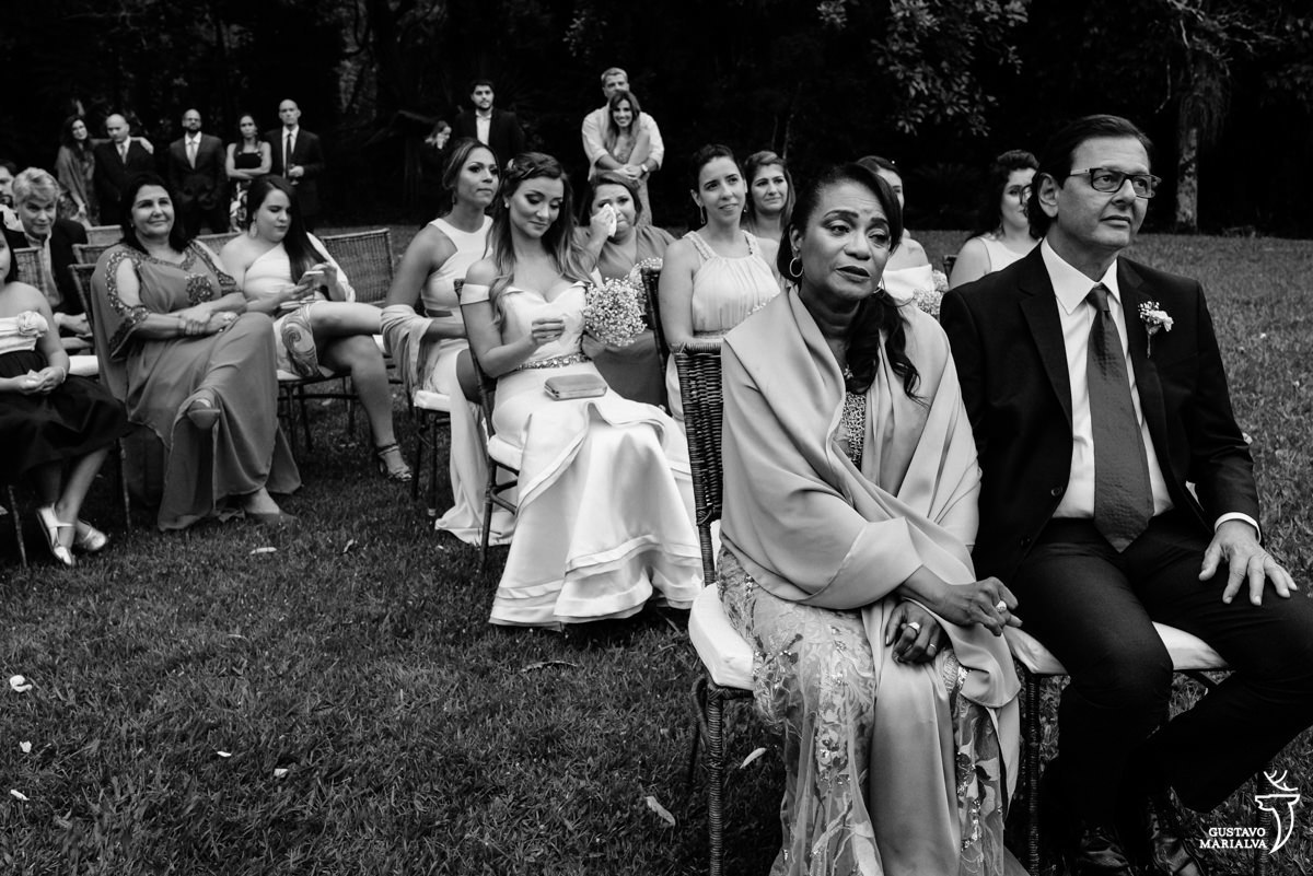 mãe da noiva chora ao escutar os votos da noiva enquanto madrinha enxuga as lágrimas ao fundo