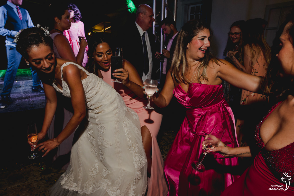 noiva dança com taça na mão e é acompanhada por amigas que usam vestido rosa