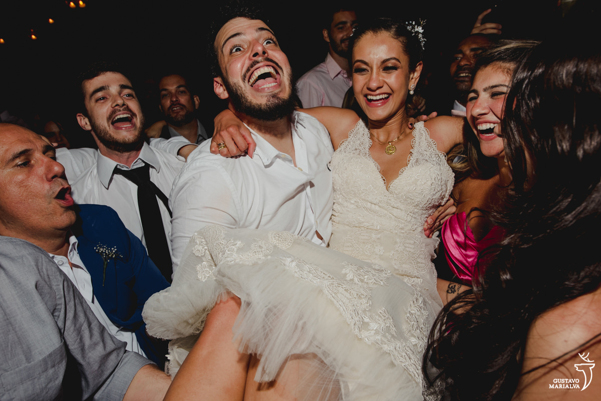 noivo carrega a noiva no colo que sorri