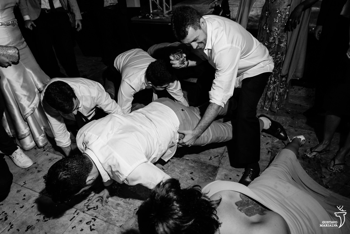 noivo dança fazendo flexão no chão e é acompanhado por amigos