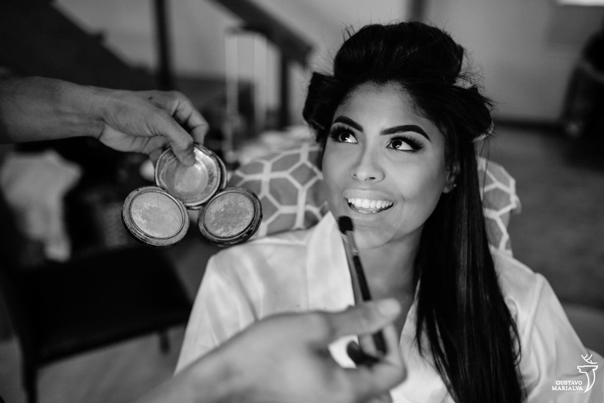 noiva olha para o maquiador enquanto ele passa blush