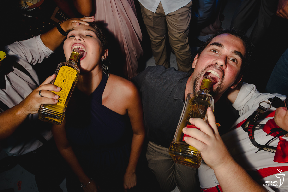 casal toma tequila ajoelhado durante a festa de casamento