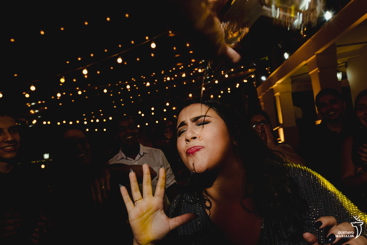 mulher derrama tequila no rosto enquanto é observada por amigos