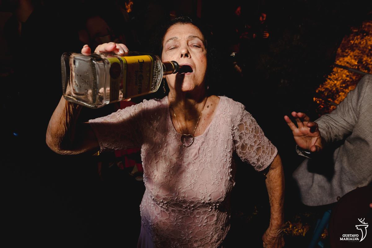 senhora usando vestido rosa toma tequila direto da garrafa