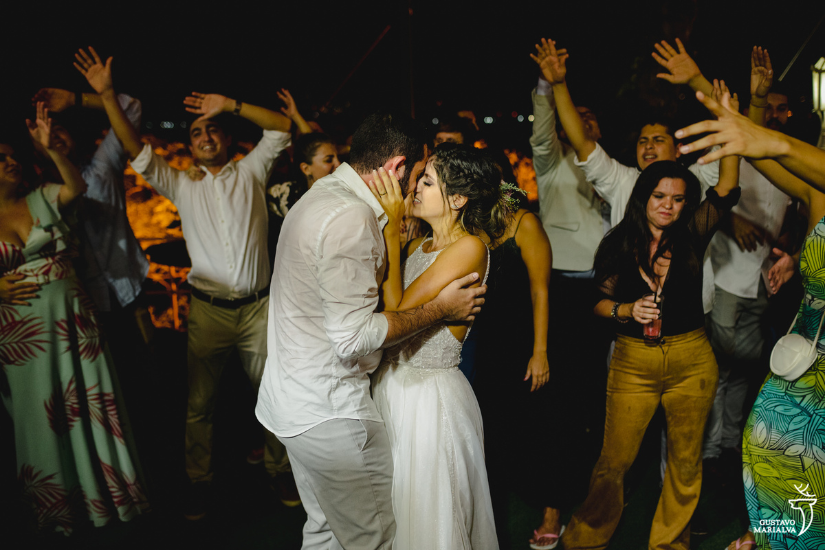noivos se beijam e convidados aplaudem ao fundo