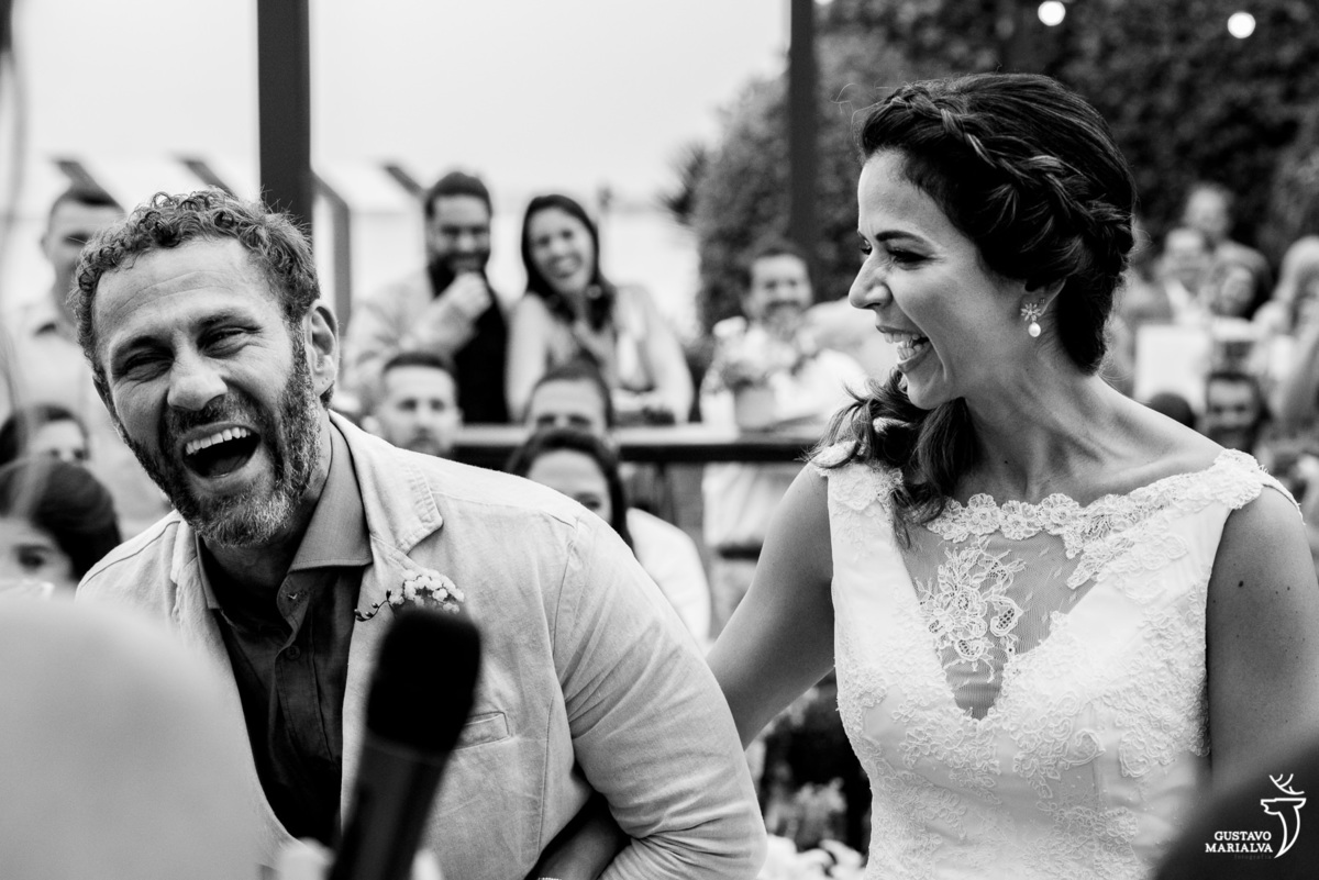 noivo usando terno caqui sorri e é observado pela noiva que usa vestido de noiva julia parker