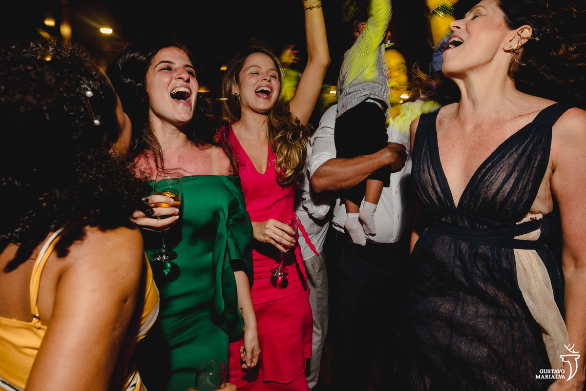 convidada usando vestido verde dança com amiga que usa vestido vermelho durante a festa de casamento 