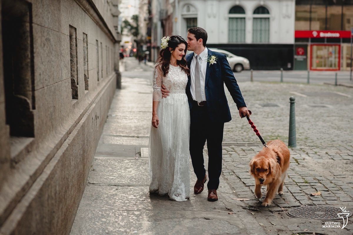 noive abraça e beija a testa da noiva enquanto caminha com cachorro