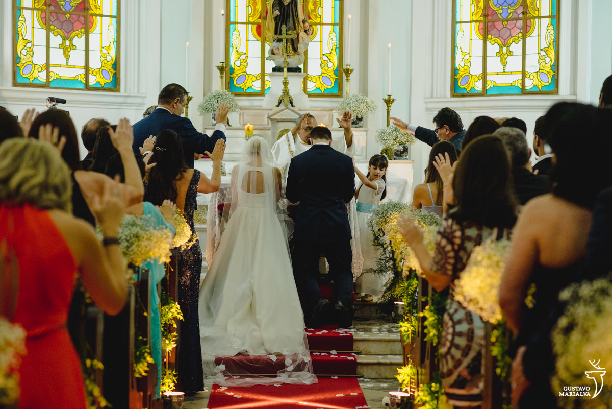 noivos ajoelhados são abençoados por convidados