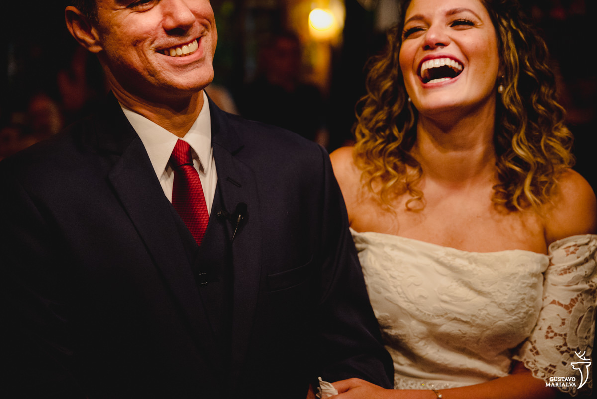 noivos sorriem de mãos dadas durante a cerimônia de casamento 