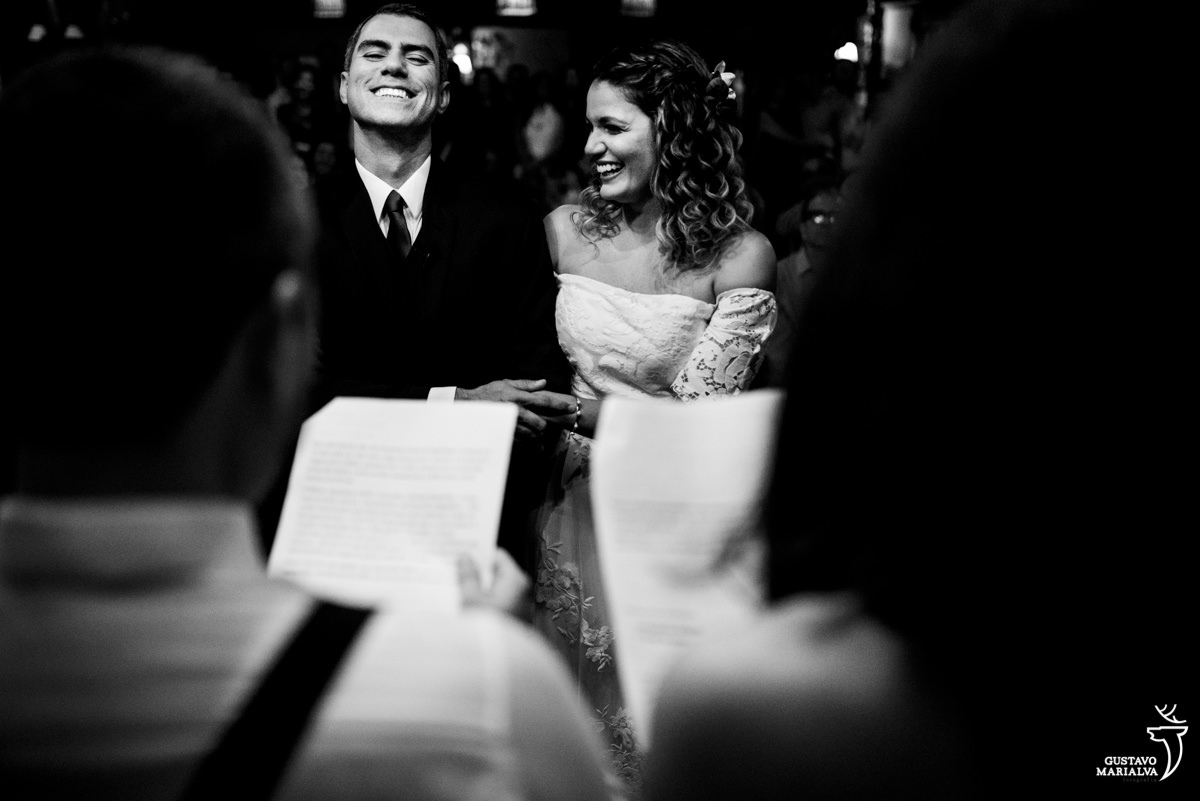 noivos sorriem enquanto escutam a cerimônia de casamento