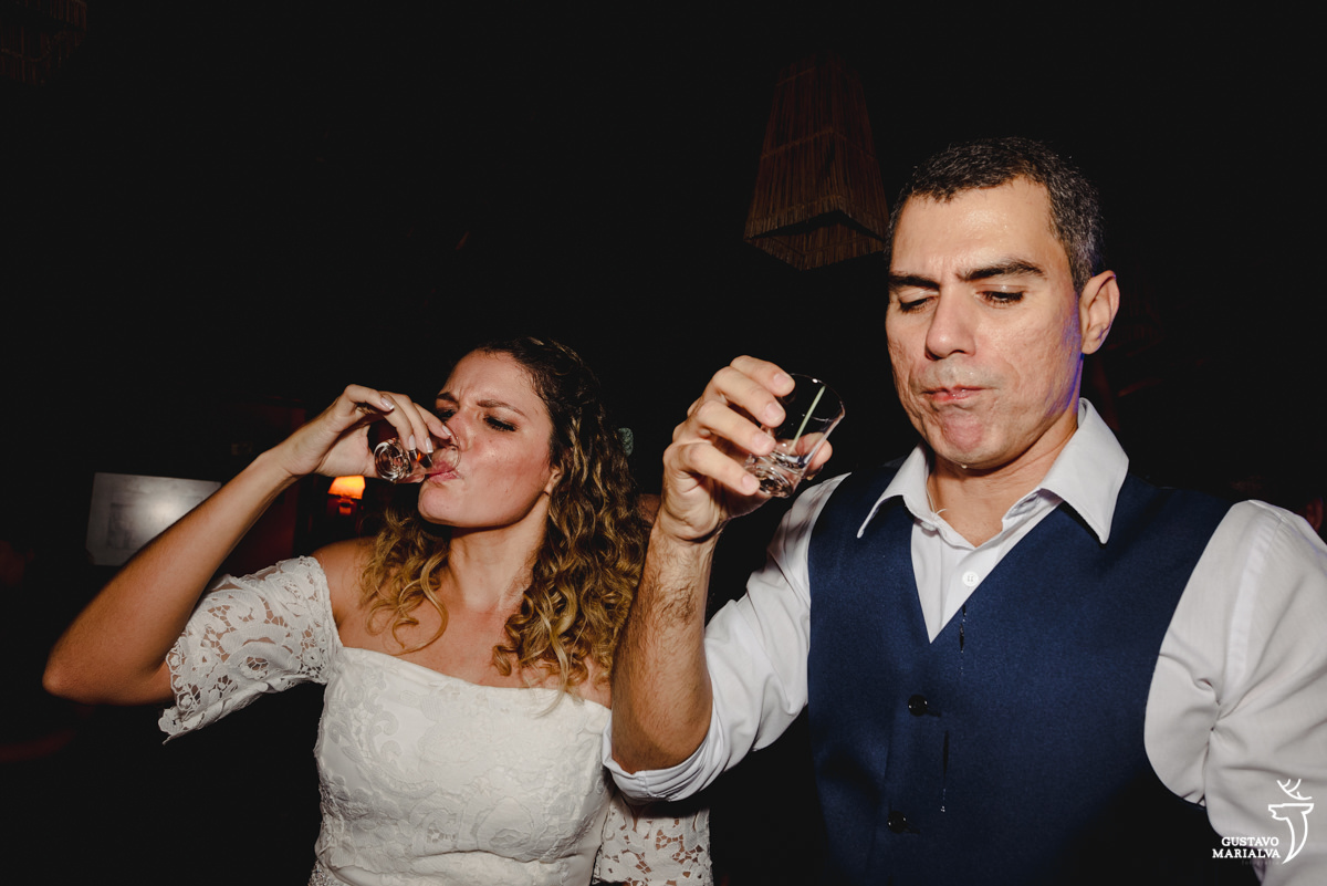 noivos tomam tequila e noivo usando colete azul deixa bebida escorrer