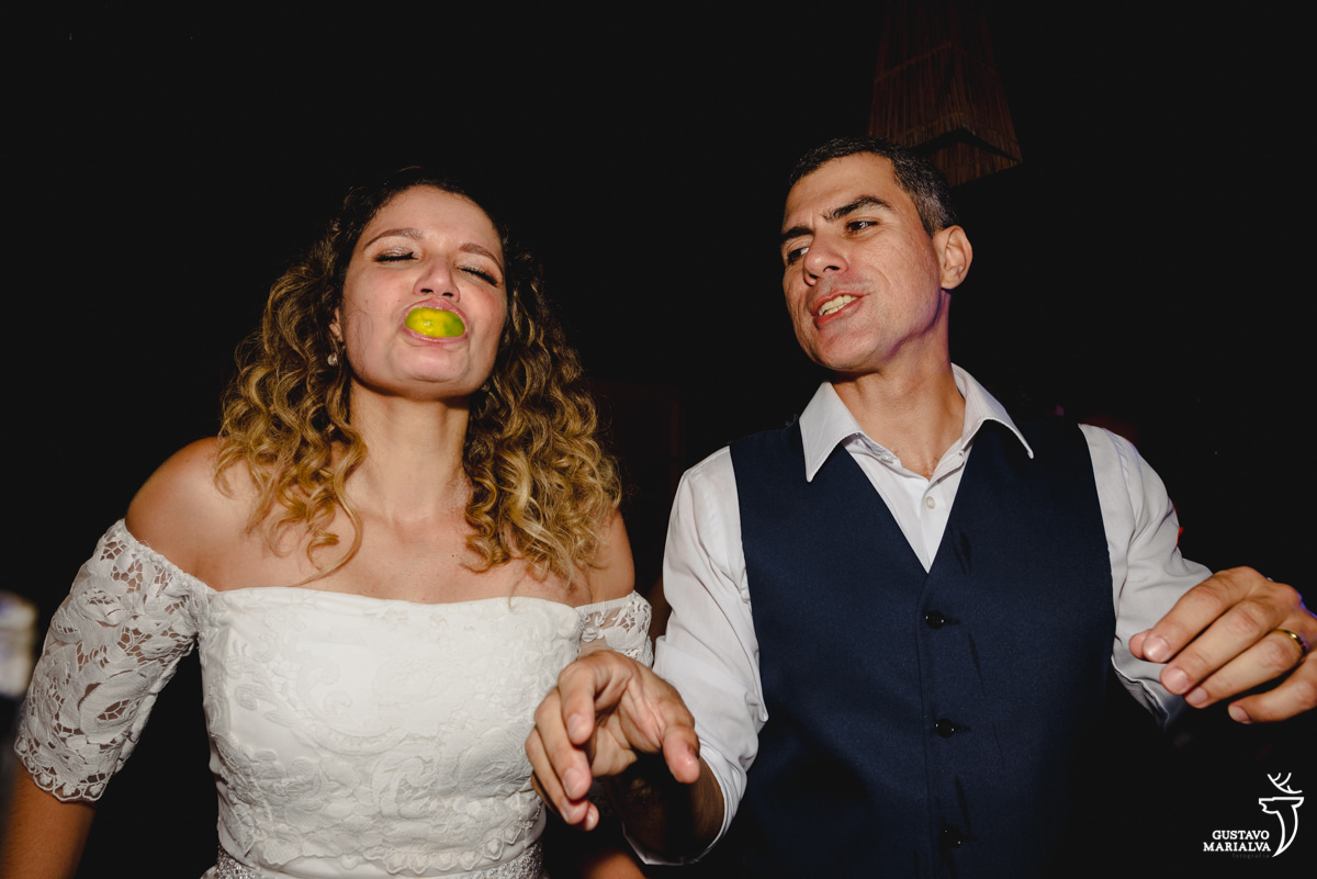 noiva faz careta com limão na boca enquanto noivo observa