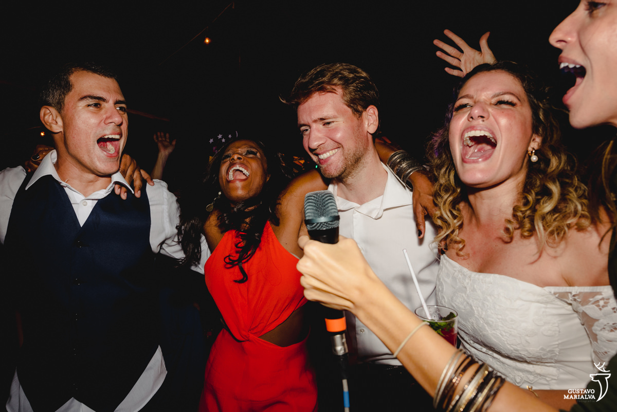 noivos dançam abraçados com amiga de vestido vermelho e homem de camisa branca 
