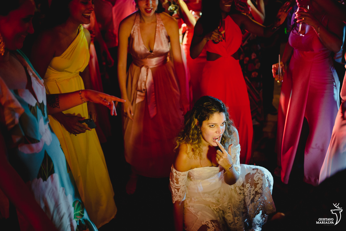 noiva dança agachada com dedo na boca enquanto amigas dançam em volta
