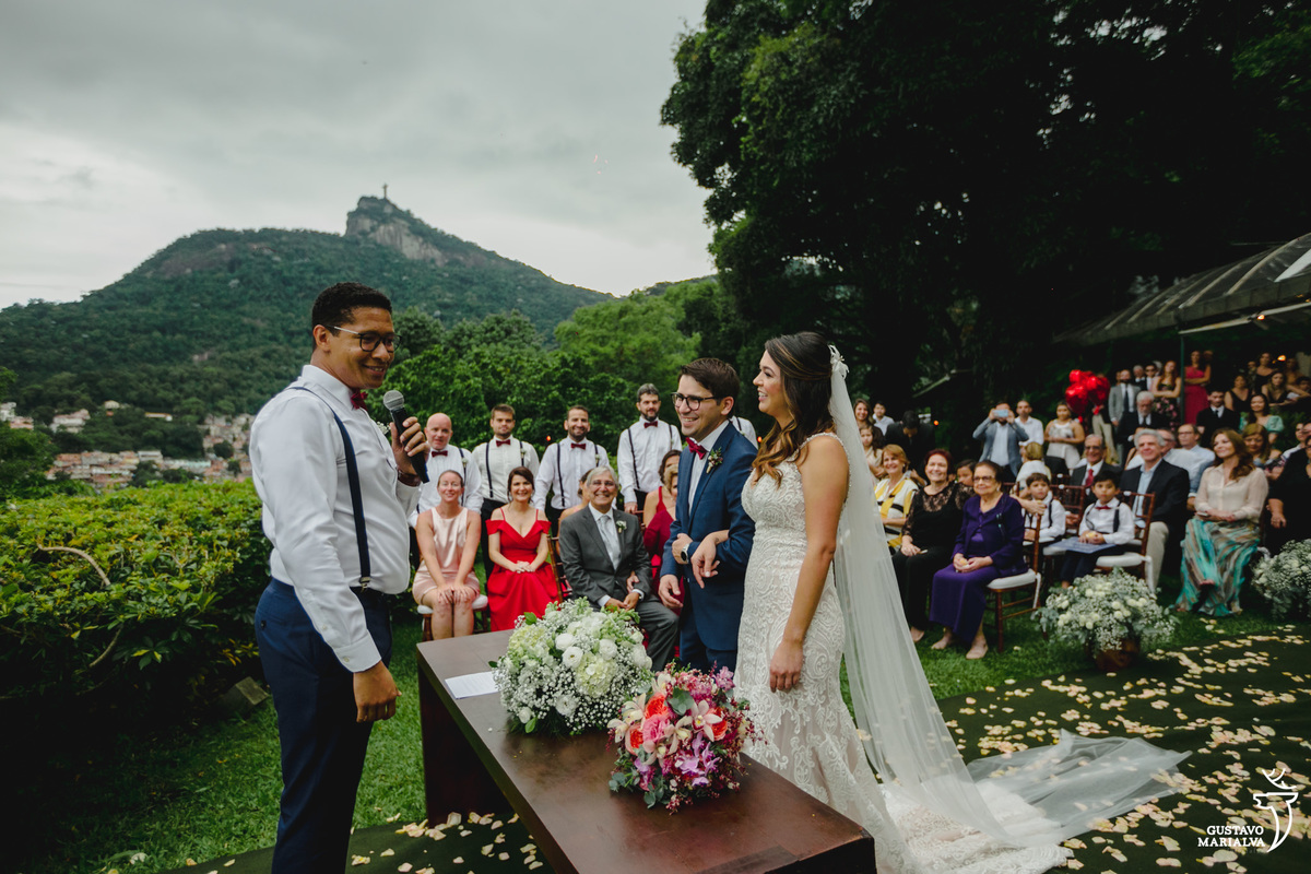 noivos escutam cerimônia com cristo redentor ao fundo