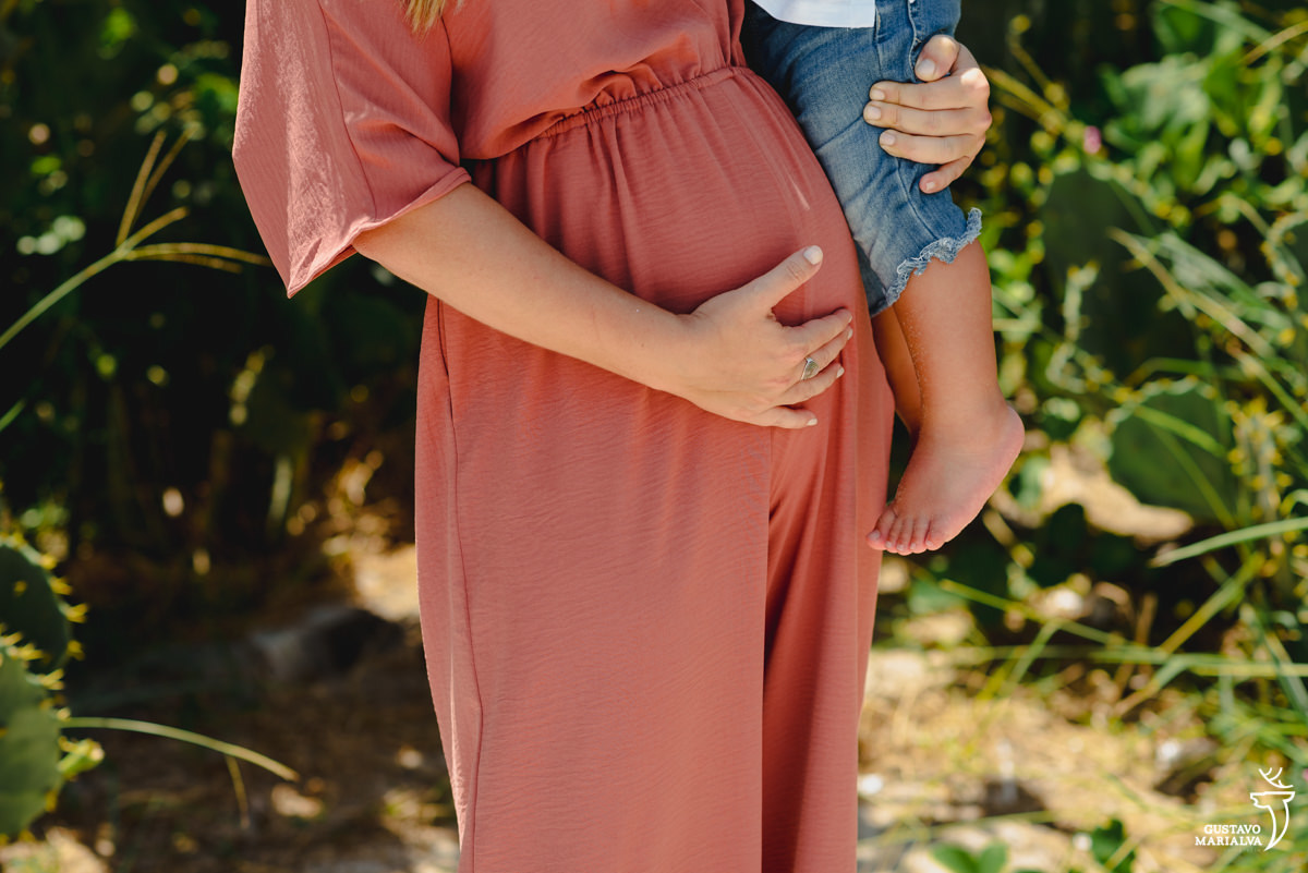 gestante de macacão terra segura o filho no colo