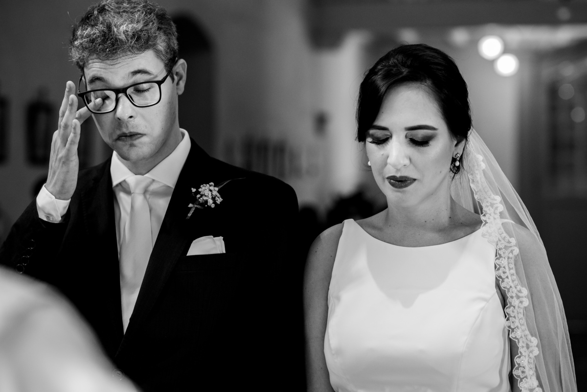 noivo de terno preto enxuga as lágrimas enquanto noiva reza 