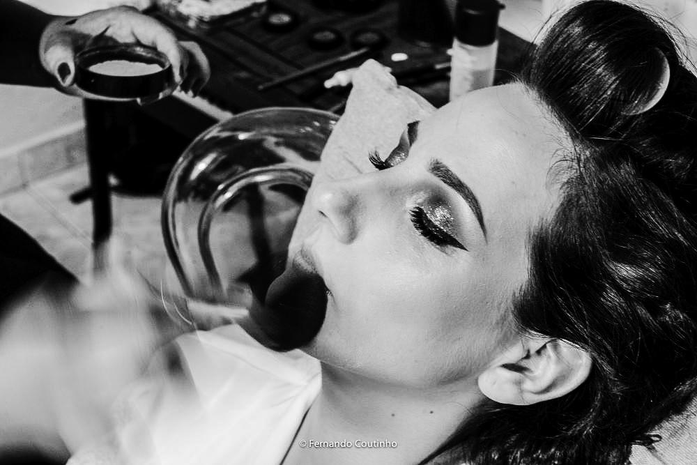 fotografia autoral de casamento da noiva se arrumando no salao no hotel da cidade de americana sao paulo. a fotografia de casamento esta com movimento na mao do maquiador.