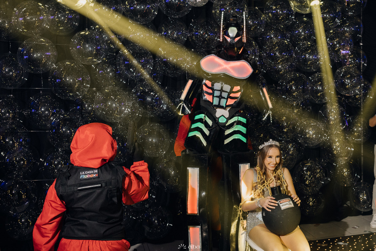Diuli no trono da festa com presença de robô de LED, durante a apresentação temática dos 15 anos no Refinatta em Venâncio Aires, por Alba Estúdio