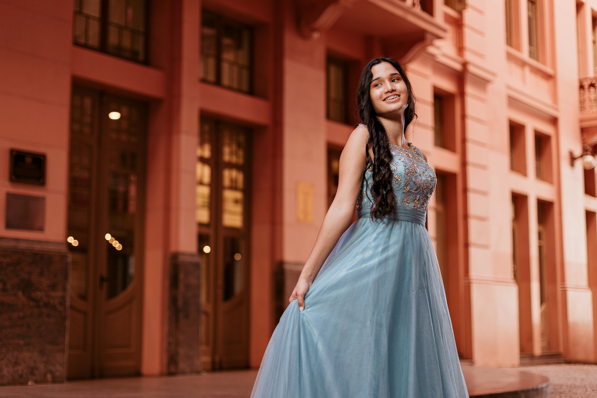 Djuly caminhando sorridente com vestido azul no Centro Histórico de Porto Alegre – ensaio de 15 anos – foto por Alba Estúdio