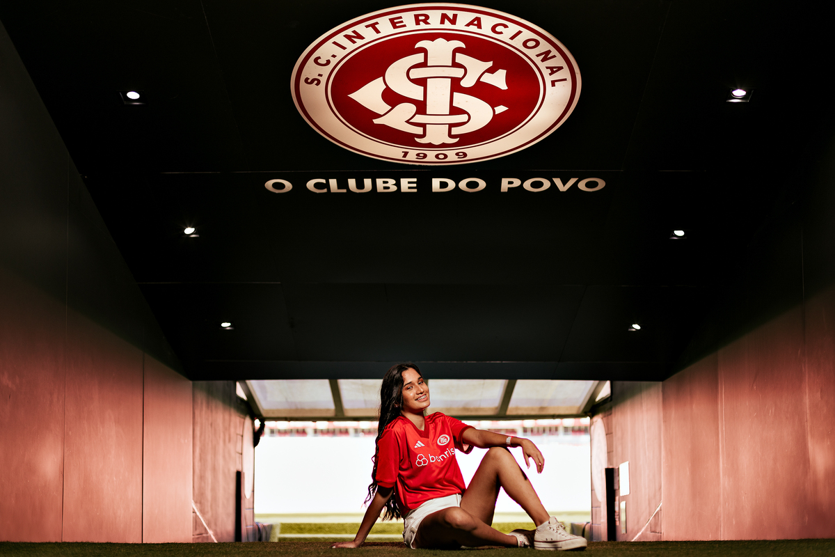 Djuly posa sentada na saída do túnel do Beira-Rio com escudo do Inter ao fundo durante ensaio de 15 anos em Porto Alegre – imagem por Alba Estúdio.