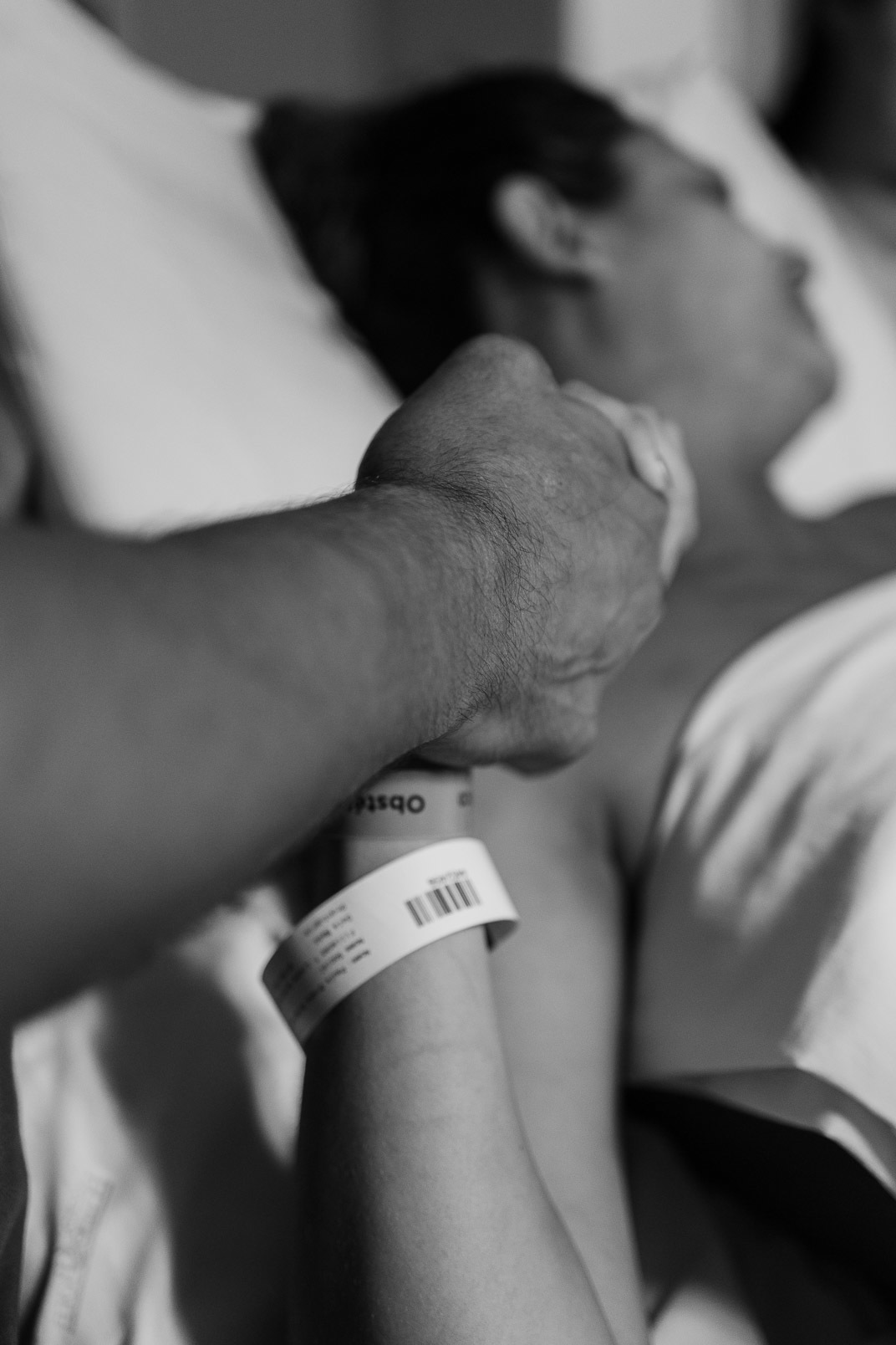 Detalhe das mãos entrelaçadas da mãe e do pai durante o parto no Hospital Bruno Born, em Lajeado — Alba Estúdio.