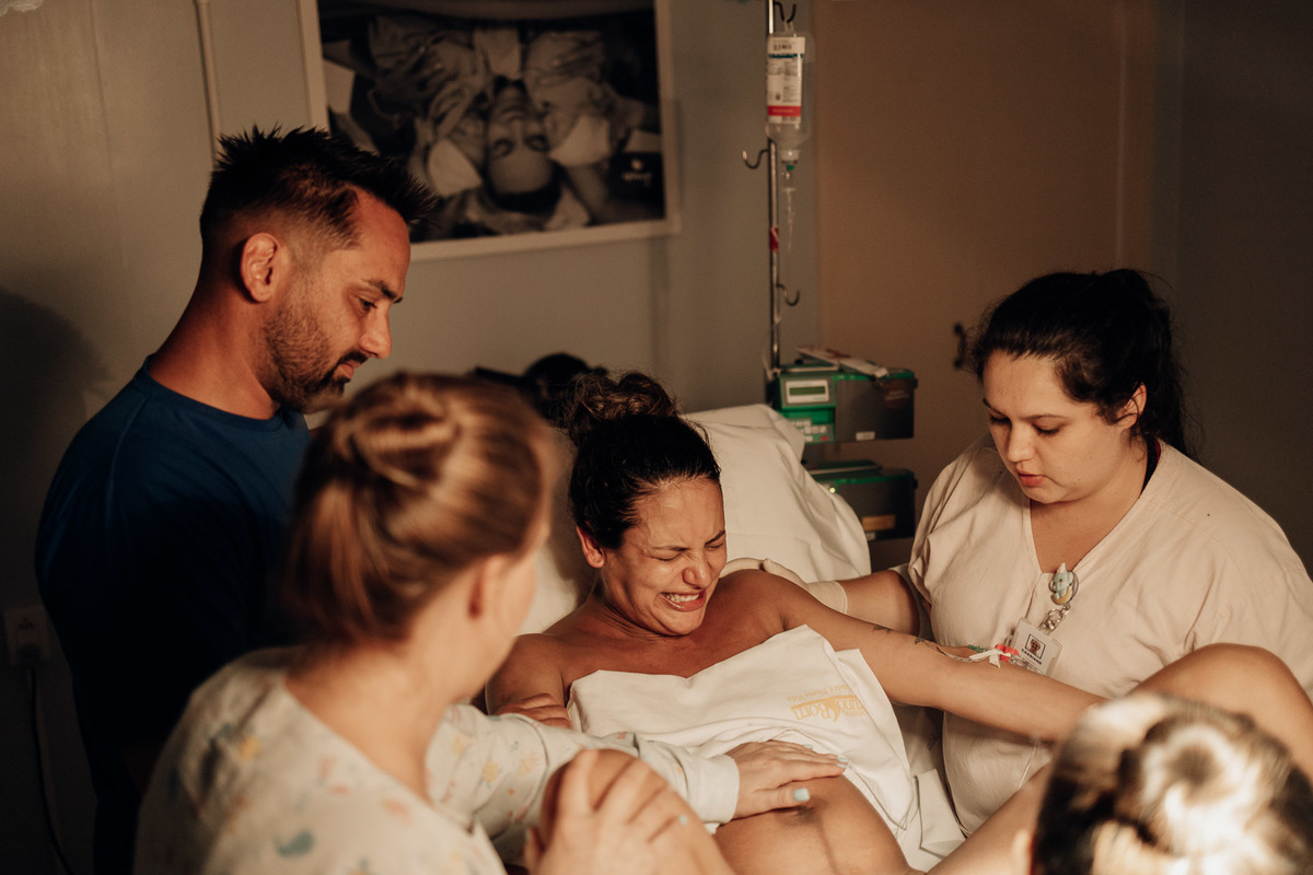 Momento intenso do nascimento com a mãe em trabalho de parto rodeada pela equipe médica no Hospital Bruno Born — Alba Estúdio.