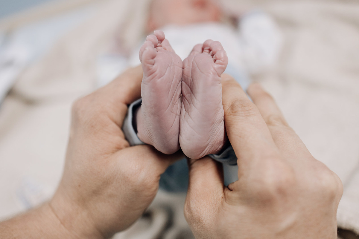 Pés enrugados do recém-nascido sendo segurados com delicadeza no Hospital Bruno Born, Lajeado