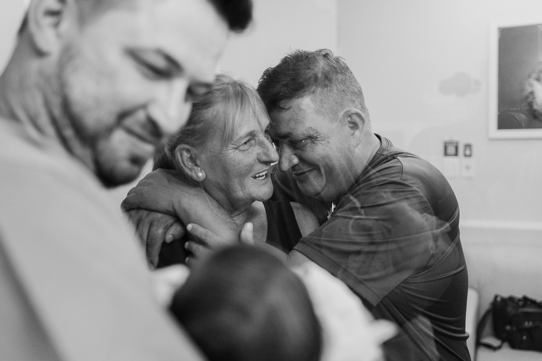 Avós abraçados e emocionados ao verem o neto pela primeira vez na maternidade”