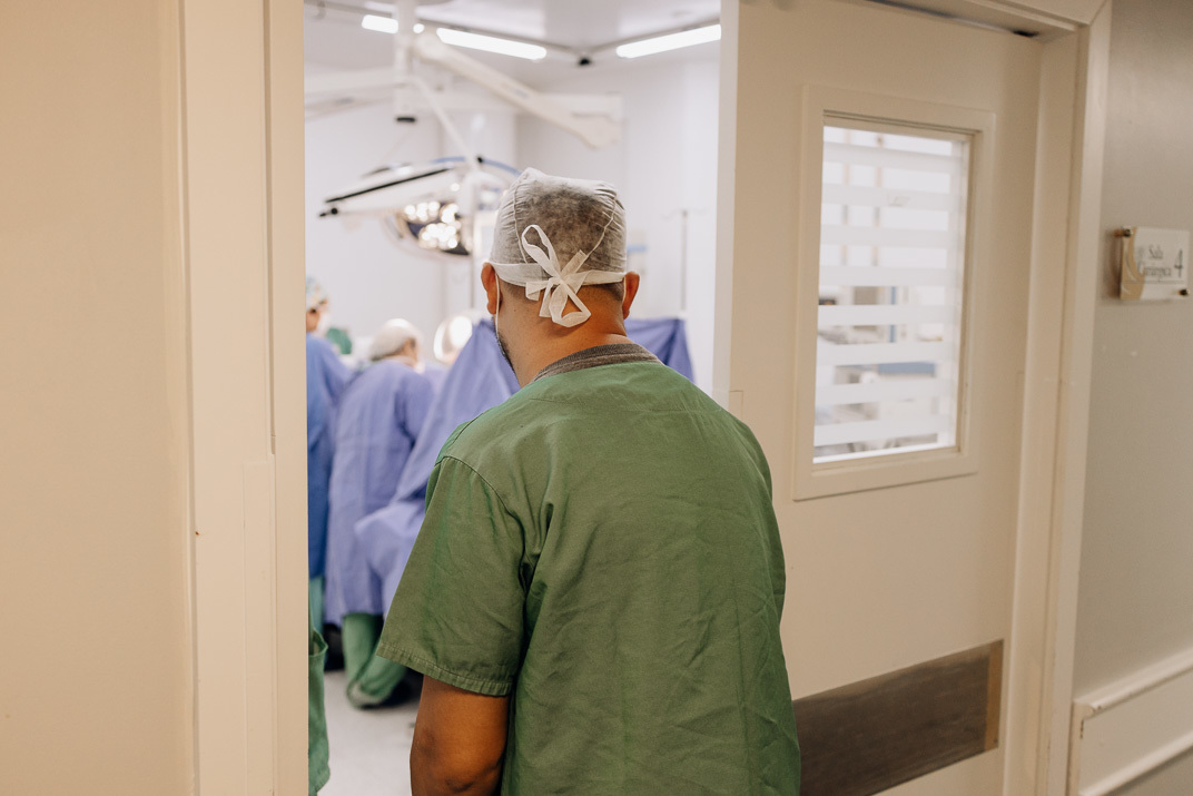 Pai observa a equipe médica preparando a sala de parto no Hospital Bruno Born, Lajeado – foto documental por Alba Estúdio.