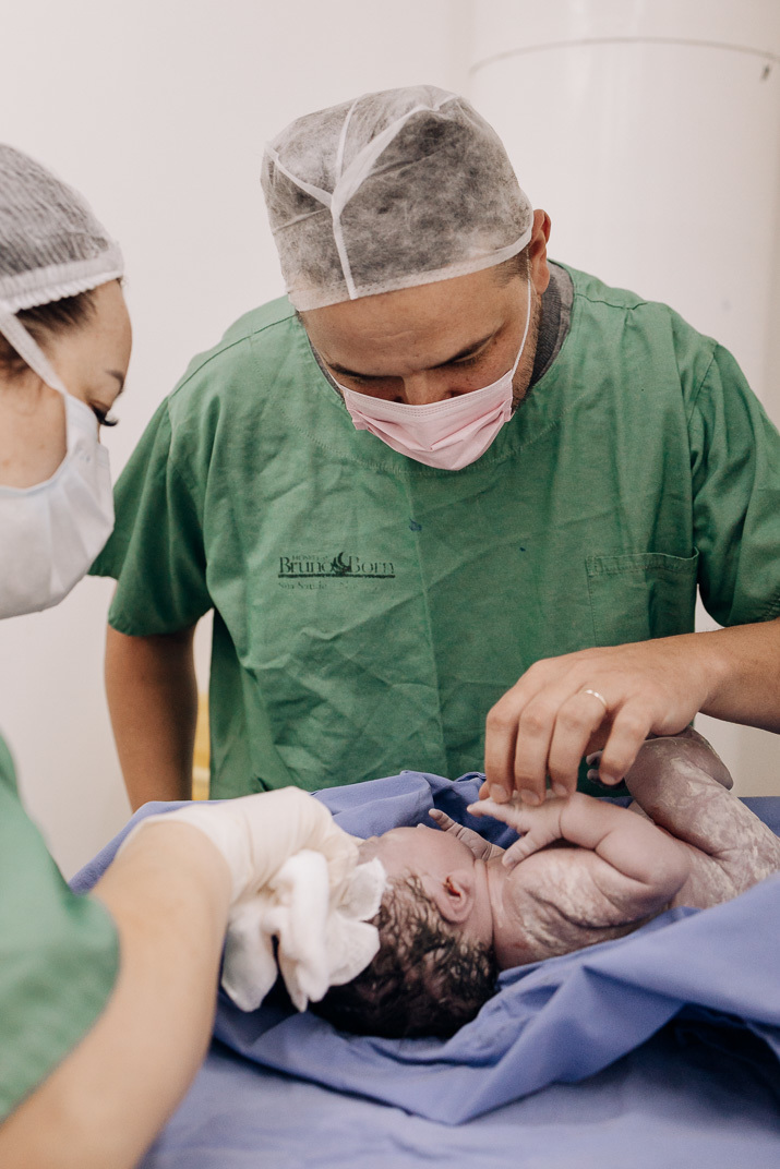 Pai emocionado observa o filho recém-nascido durante o parto no Hospital Bruno Born em Lajeado – registro feito pelo Alba Estúdio.