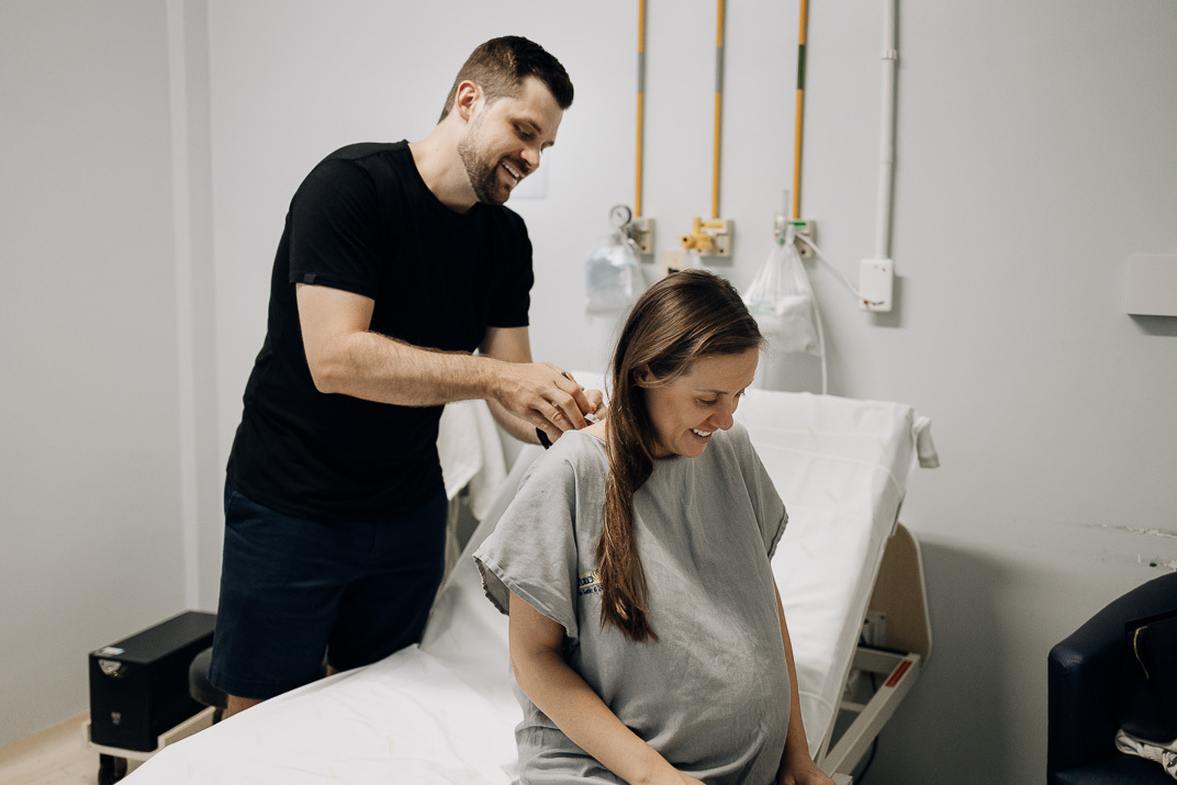 Pai ajeita cabelo da esposa gestante enquanto ela aguarda parto no Hospital Bruno Born