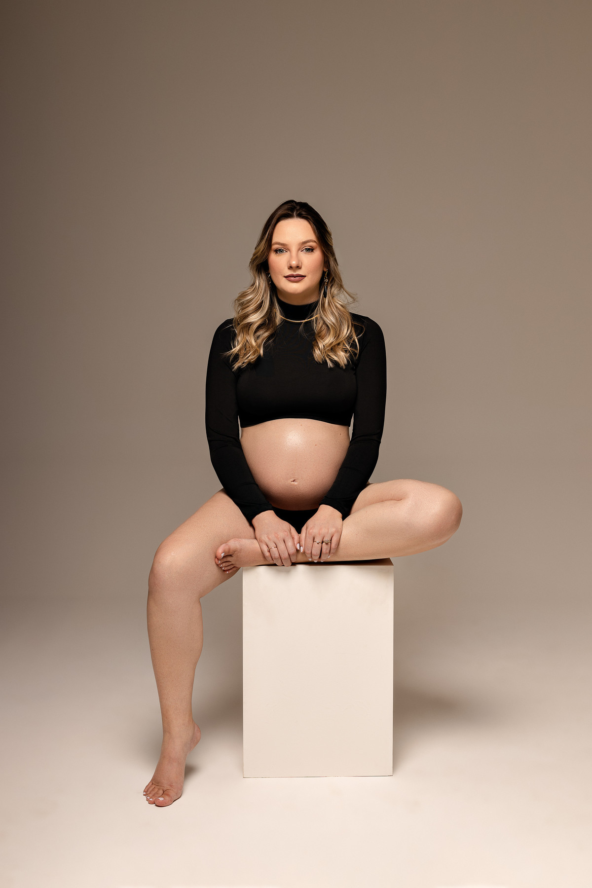 gestante-sentada-cube-branco-estudio