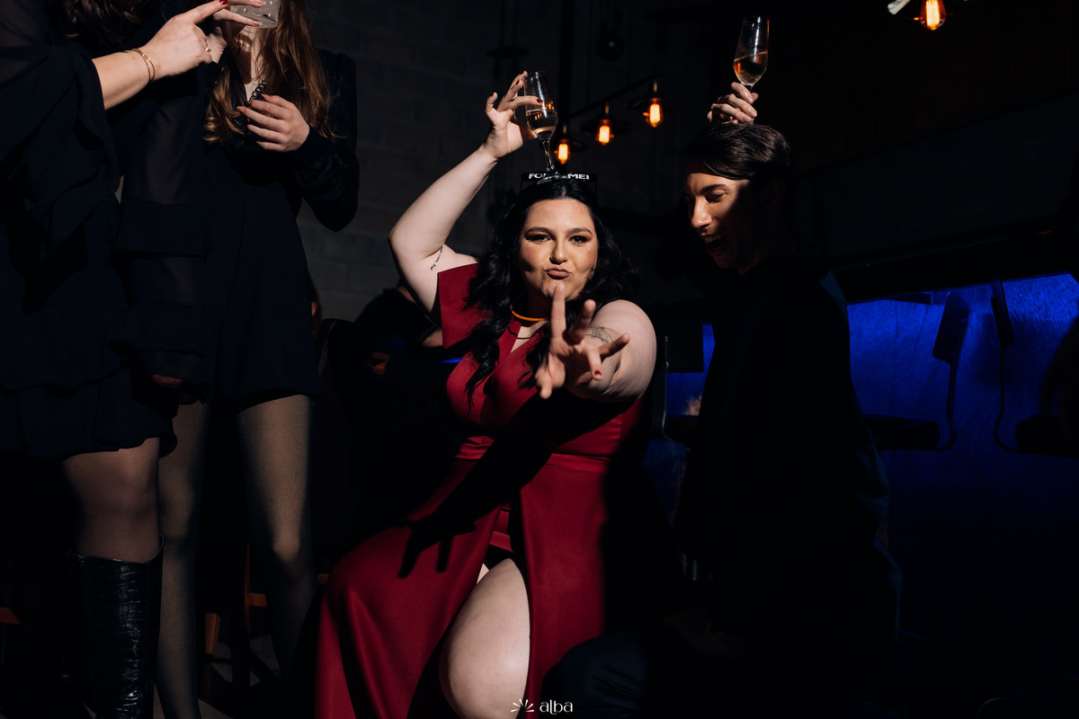 Carolina de vestido vermelho dançando e apontando para a câmera na festa de formatura no Bierdron, Lajeado.